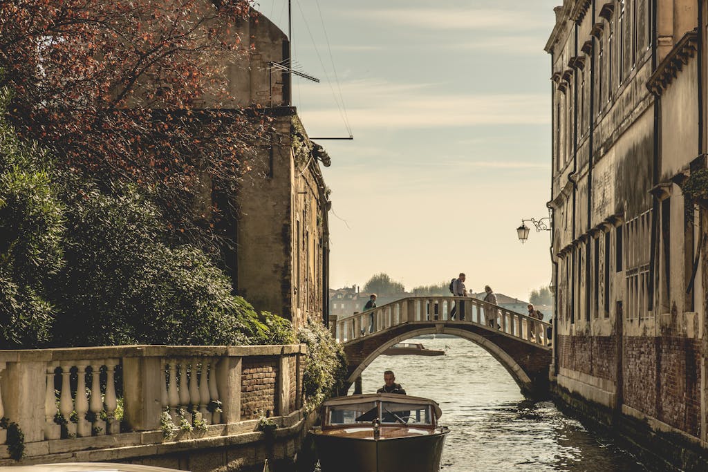 Captivating view of a Venetian canal with a bridge and boat, showcasing historic architecture.